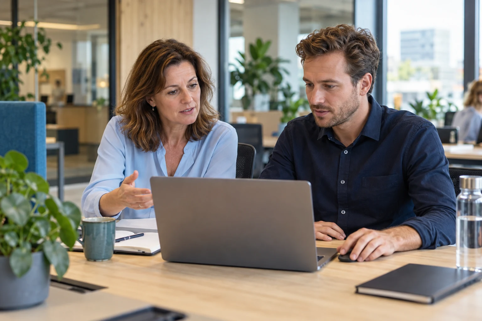 Illustratie van twee collega’s die samen oefenen met een zakelijke taak op een laptop